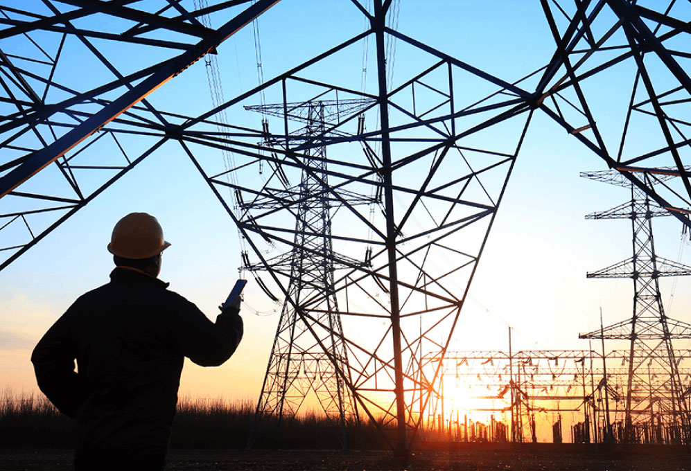 Profesional en terreno junto a torres de transmisión eléctrica